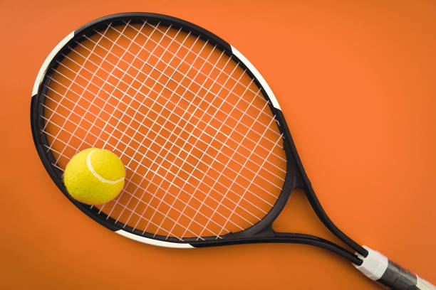 Tennis racket and tennis ball on the orange clay court stock photo