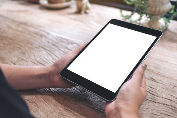 istock Mockup image of hands holding black tablet pc with blank white screen on vintage wooden table 998257190