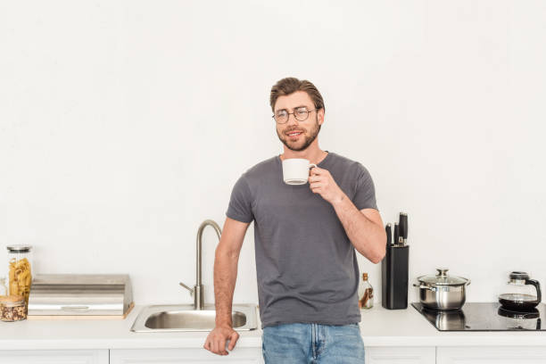istock front view of smiling young man in eyeglasses drinking coffee at kitchen 998271574