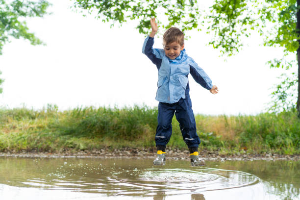 istock little boy jumping in rain puddle 998271770