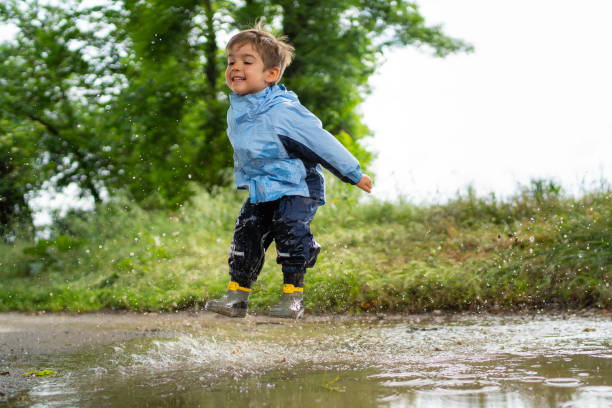 istock one boy jumping in rain pudle 998271792