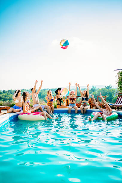 Friends playing with beach ball in swimming pool Having fun with friends at the swimming pool in summer pool party stock pictures, royalty-free photos & images