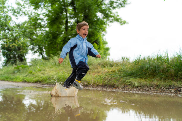 happy laughing little boy running through rain puddle