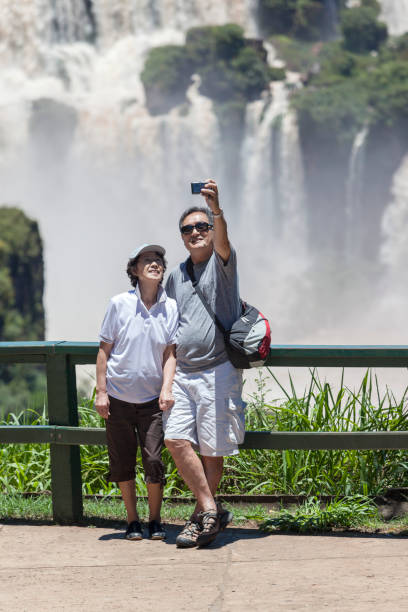 casal brasil de turistas nas férias tomando selfie na frente cataratas em iguaçu - iguacu national park - fotografias e filmes do acervo