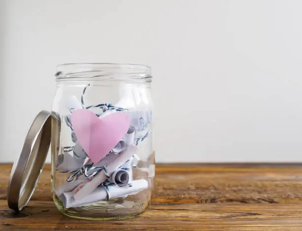 Photo of Jar with pink heart and rolled-up notepads