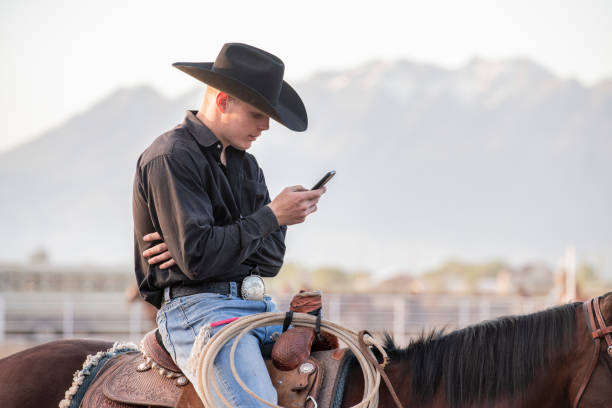 Young cowboy turning his head, looking with a skeptical smile, grin towards the camera. Real Rodeo People Portrait. Spanish Fork, Utah, USA