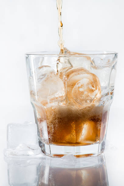 istock stream of cola is poured into a glass with ice 998304390