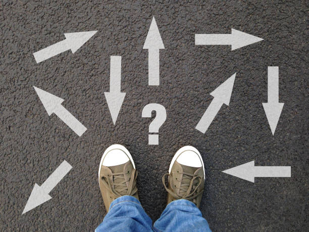 istock feet standing on asphalt with multitude of arrows in diffrent directions 998306192