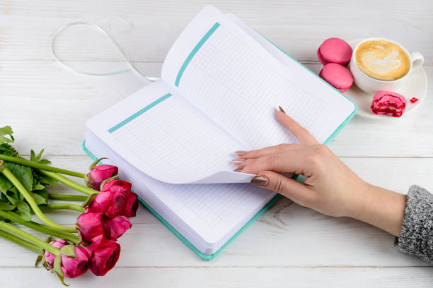 istock Close notebook, cup of coffee and tulips on light wooden backgro 998312576