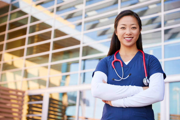 sonriendo asiática trabajadora profesional de la salud con los brazos cruzados - asistente sanitario fotos fotografías e imágenes de stock