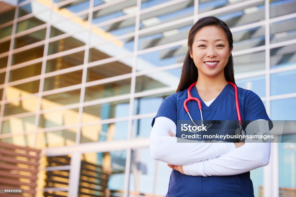 Smiling Asian female healthcare worker with arms crossed Nurse Stock Photo