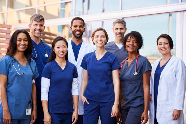 squadra medica sorridente in piedi insieme fuori da un ospedale - health profession foto e immagini stock