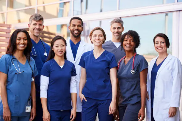 Photo of Smiling medical team standing together outside a hospital
