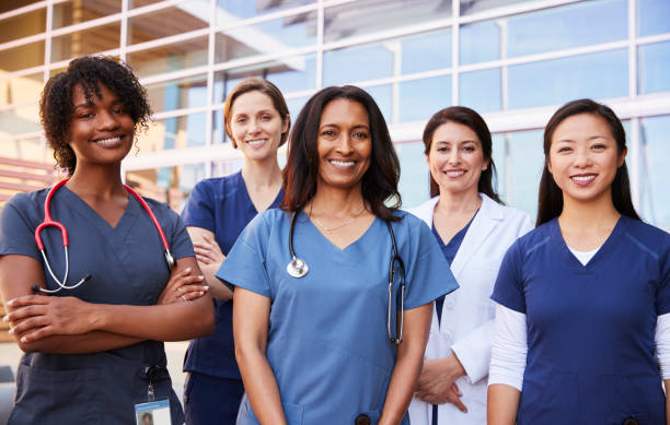 Female healthcare colleagues standing outside hospital Female healthcare colleagues standing outside hospital lab coat photos stock pictures, royalty-free photos & images