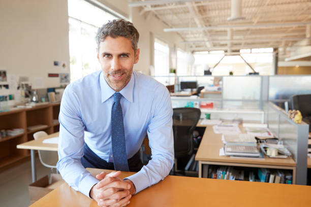 istock Male architect leaning on desk in office looking to camera 998313862