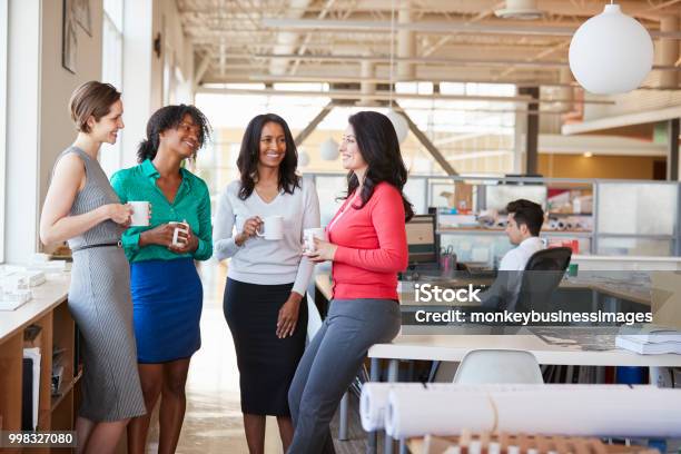 Female Work Colleagues Chatting Over Coffee In The Office Stock Photo - Download Image Now