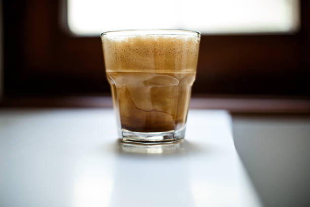 A glass of iced coffee with milk on a white table A glass of iced coffee with milk and foam lying on a white table freddo cappuccino stock pictures, royalty-free photos & images