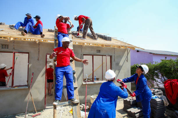 Diverse Community members join PWC's staff in building a low cost house in Soweto Soweto, South Africa, September 10, 2011, Diverse Community members join PWC's staff in building a low cost house as a team in Soweto soweto stock pictures, royalty-free photos & images