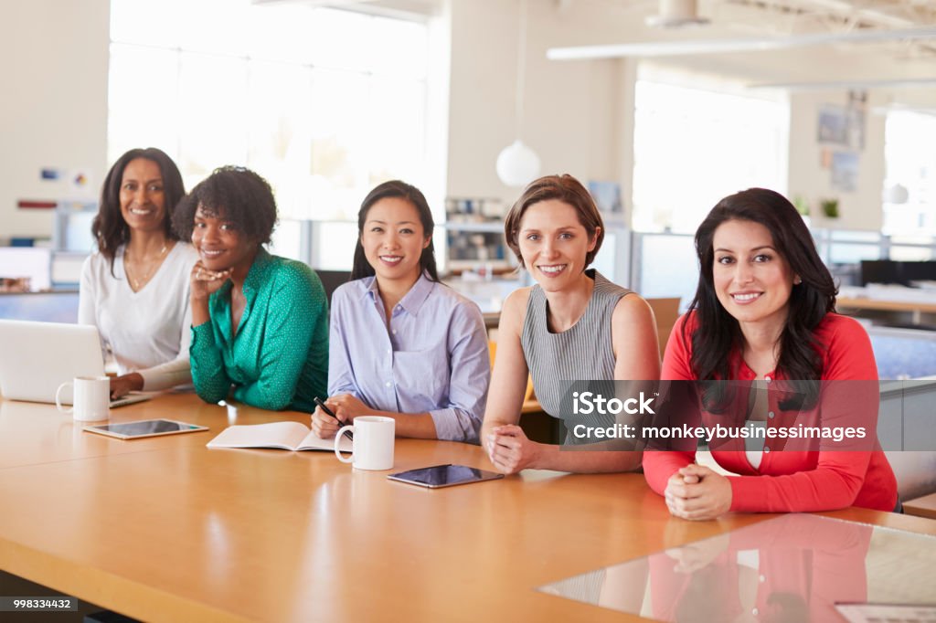 Compañeros de trabajo femenino en una oficina, sonriendo a la cámara - Foto de stock de Sólo mujeres libre de derechos