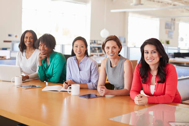 коллеги-женщины в офисе улыбаются на камеру - chinese ethnicity latin american and hispanic ethnicity multi ethnic group business person стоковые фото и изображения