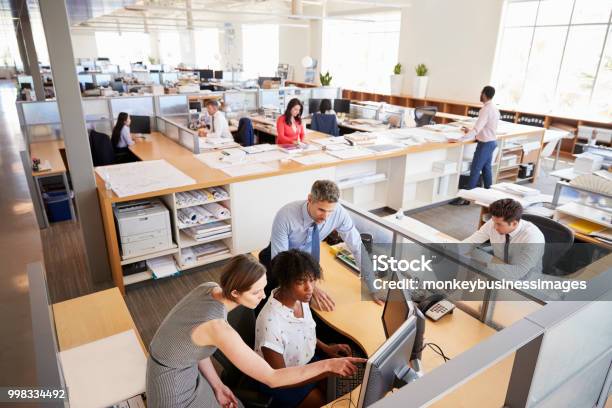 Colleagues Working At A Womanâu20acs Workstation In A Busy Office Stock Photo - Download Image Now