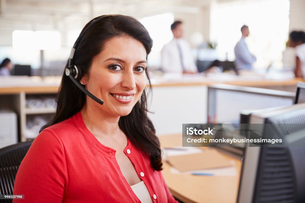 Hispanic woman working in a call centre smiling to camera Customer Service Representative Stock Photo