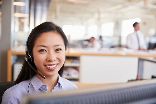 istock Young Asian woman working in a call centre smiling to camera 998337406