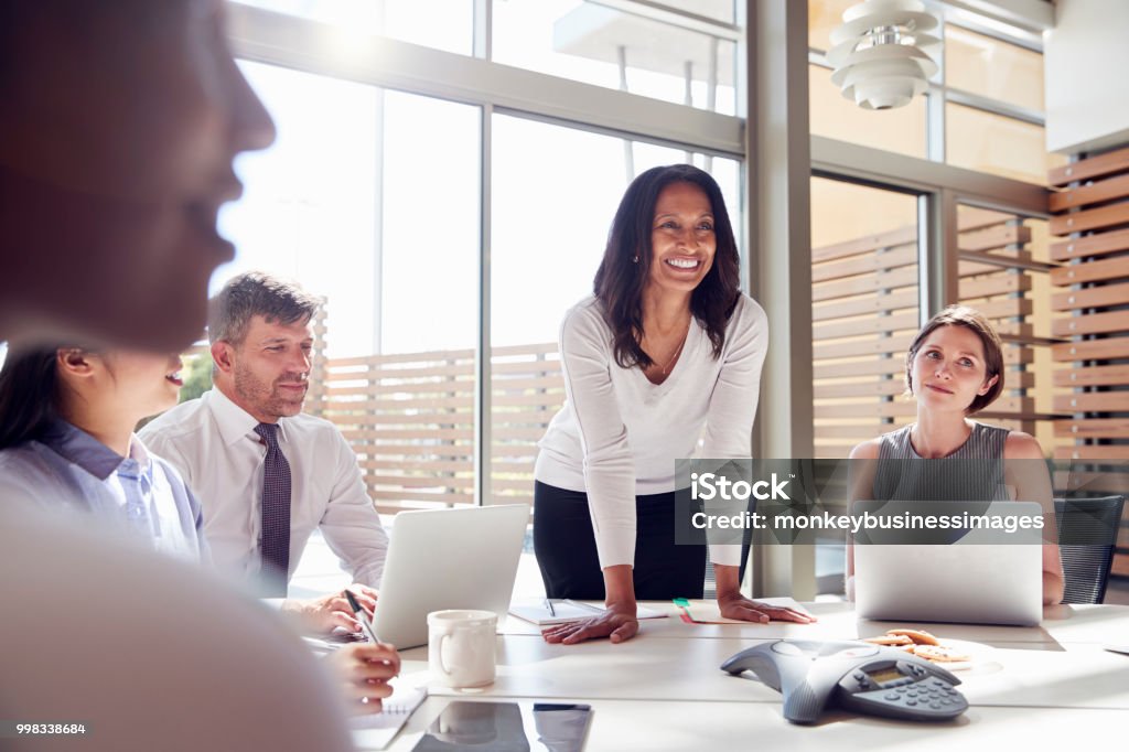 笑顔の女性マネージャー会議で同僚に聞いて - リーダーシップのロイヤリティフリーストックフォト