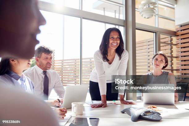 笑顔の女性マネージャー会議で同僚に聞いて - リーダーシップのストックフォトや画像を多数ご用意 - リーダーシップ, 会議, 女性