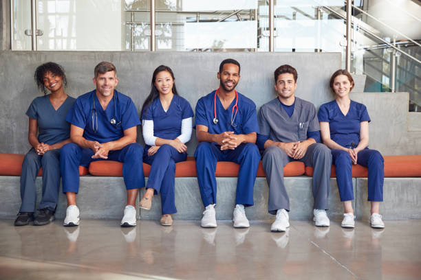 travailleurs de la santé assis dans un hôpital moderne, à angle faible - healthcare and medicine smiling group of people lab coat photos et images de collection