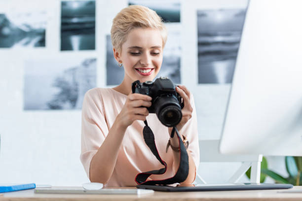 istock happy female photographer looking at camera screen at table with computer in home office 998339444