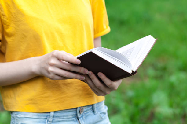 istock Young female reading book in summer park 998372282
