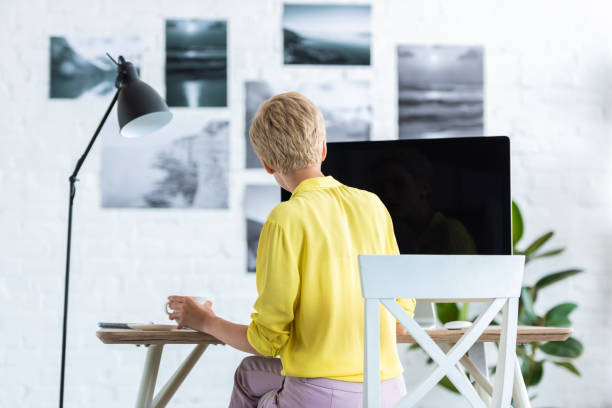 istock rear view of businesswoman drinking coffee and working on computer at table 998372862