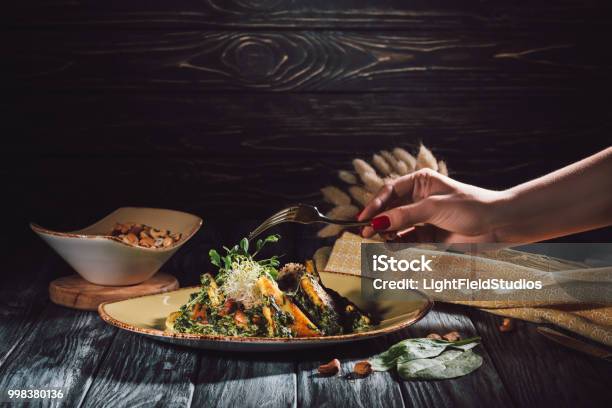 Cropped Image Of Woman Eating Panikesh With Cashew Nuts And Spinach By Fork Over Table Stock Photo - Download Image Now