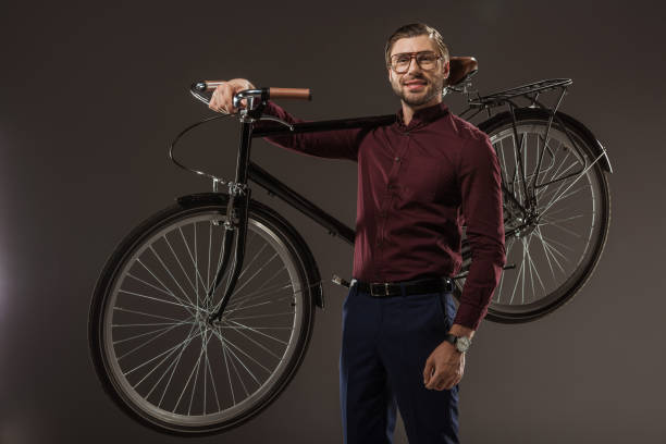 handsome man in eyeglasses holding bicycle and smiling at camera on black