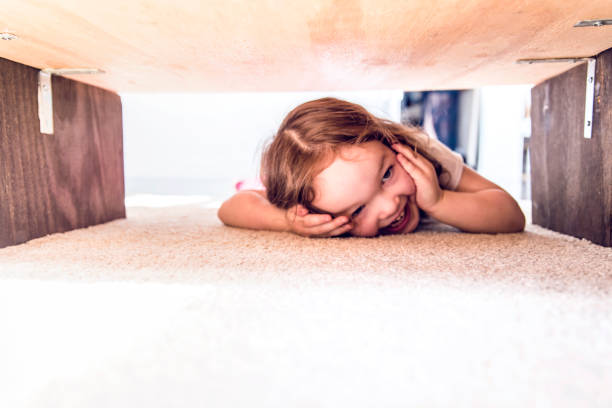 istock Playful baby girl playing hiding under a table 998403904