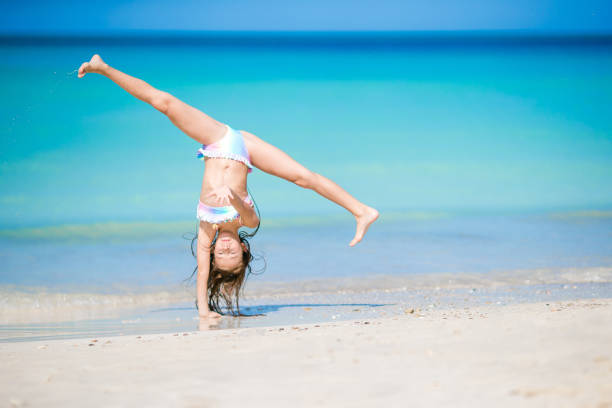 Active little girl at beach having a lot of fun. Cute kid making sporty exercises on the seashore