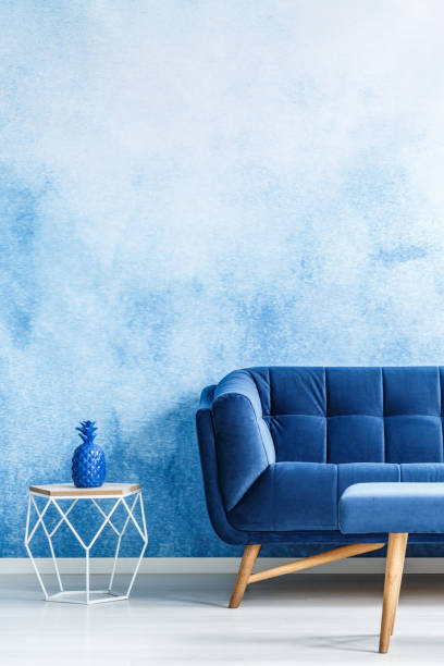 istock Copy space monochromatic living room interior with plush, navy blue couch and metal side table against ombre wall. Real photo. 998418964