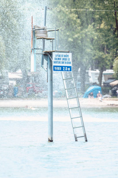 An unoccupied lifeguard chair with message on the sign. Text in French. The beach is open only when lifeguards are on homework. Depth 2.0 M.