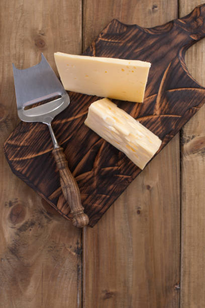 cheese with holes is cut into portions on a wooden board, a useful dairy product. tasty food. country style photo. place for text. copy space - cheese emmental cheese switzerland grated imagens e fotografias de stock