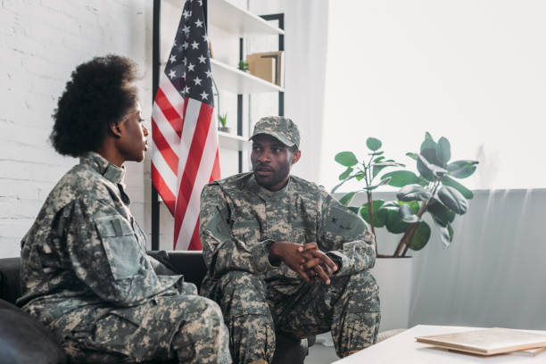 istock Woman and man in army uniform talking on sofa at home 998428998