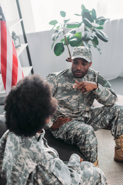istock Couple or army soldiers talking on sofa at home 998429004