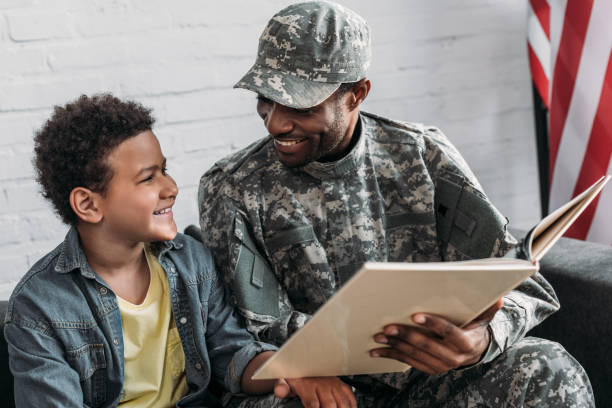 istock African american man in camouflage clothes and boy reading book 998429022
