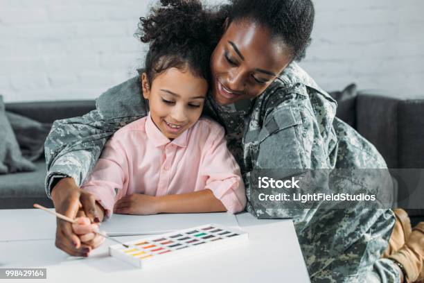 African American Female Soldier With Daughter Drawing With Watercolor Paint Stock Photo - Download Image Now