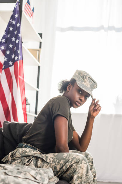 istock Young female soldier in camouflage clothes sitting on sofa 998429406
