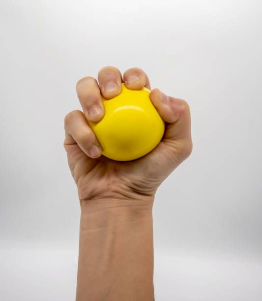 istock Hand holding yellow stress ball isolated on white background. 998432784