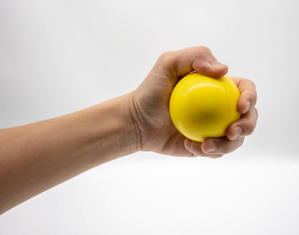 istock Hand holding yellow stress ball isolated on white background. 998432792