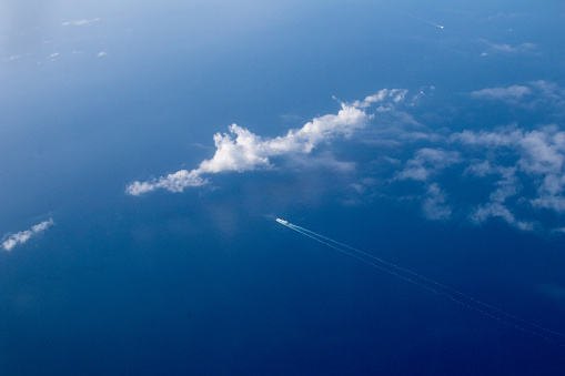 Cuise ship seen from the plane in the mediterranean. Ship in the open sea that leaves behind it, a cloud on the left.