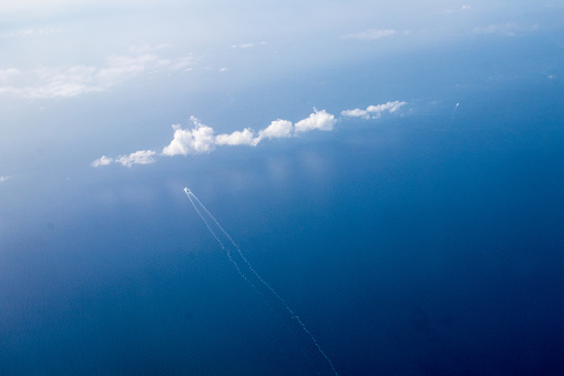 Cuise ship seen from the plane in the mediterranean. Ship in the open sea that leaves behind it, a cloud on the left.