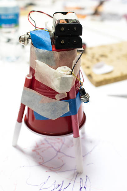Plastic cup with DC motor and batteries writing with a marker on white sheet of paper.